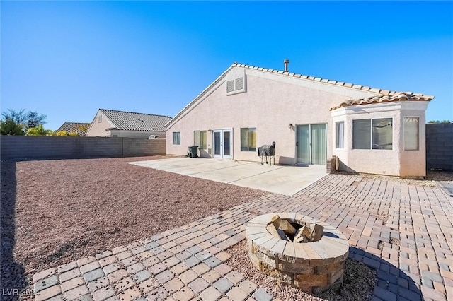 rear view of property with a patio area and a fire pit