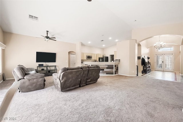 carpeted living room featuring french doors, ceiling fan with notable chandelier, and lofted ceiling