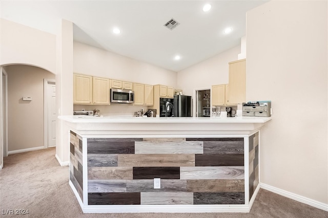 kitchen with cream cabinets, light colored carpet, black fridge, and lofted ceiling