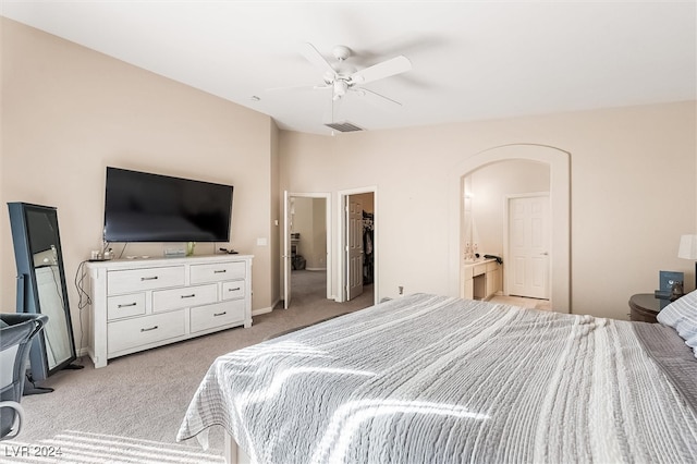 bedroom featuring a walk in closet, light carpet, a closet, and ceiling fan