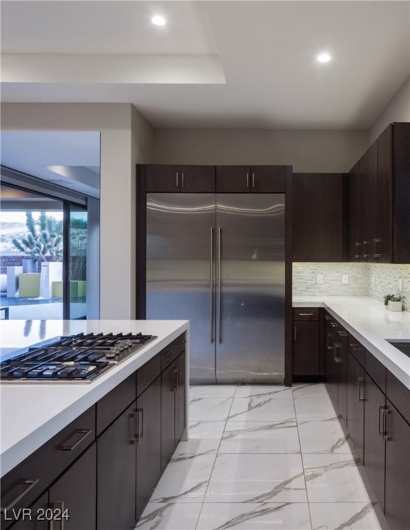 kitchen with dark brown cabinetry, decorative backsplash, and appliances with stainless steel finishes