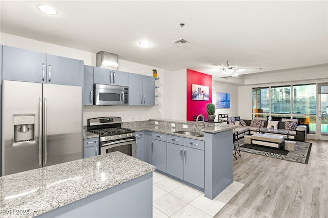 kitchen featuring ceiling fan, sink, light stone counters, kitchen peninsula, and appliances with stainless steel finishes