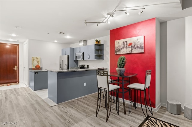 kitchen featuring track lighting, gray cabinets, a kitchen island, appliances with stainless steel finishes, and light hardwood / wood-style floors