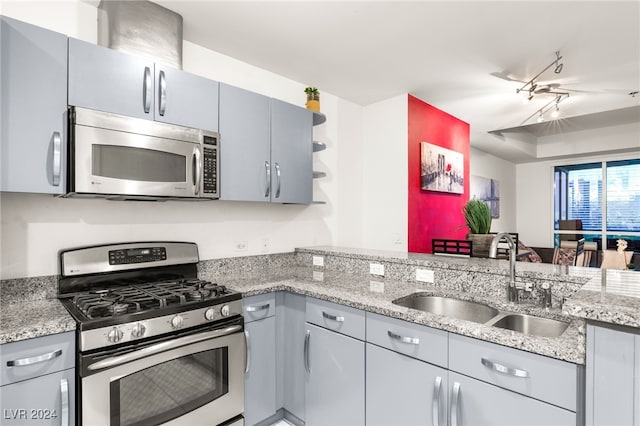 kitchen featuring sink, gray cabinets, light stone countertops, kitchen peninsula, and stainless steel appliances