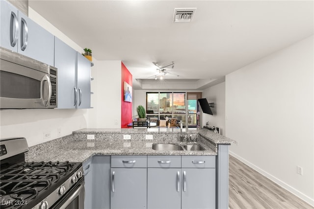 kitchen featuring light stone countertops, kitchen peninsula, sink, and appliances with stainless steel finishes