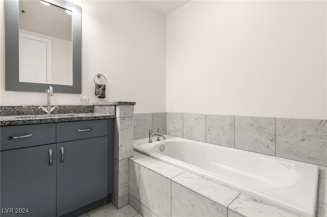 bathroom featuring tile patterned floors, tiled bath, and vanity