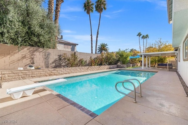 view of swimming pool featuring a diving board and a patio