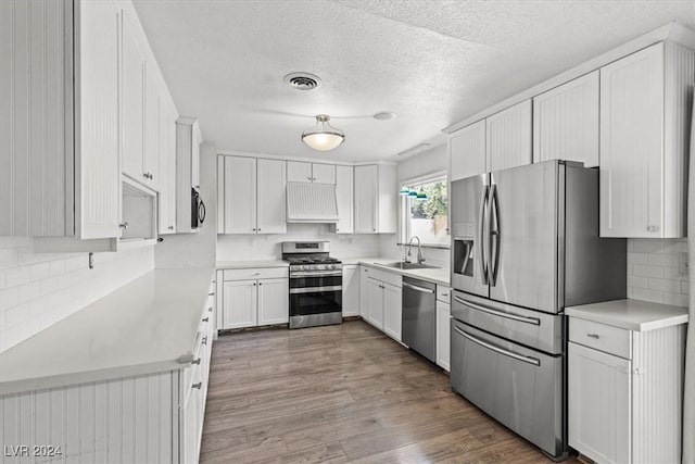 kitchen featuring white cabinetry, sink, dark wood-type flooring, stainless steel appliances, and extractor fan