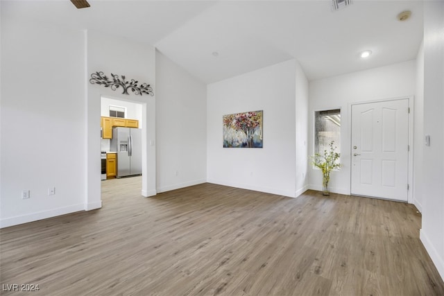 interior space featuring light wood-type flooring and vaulted ceiling