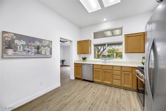 kitchen with light wood-type flooring, stainless steel appliances, ceiling fan, and sink