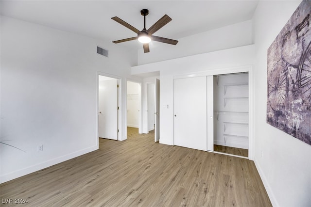 unfurnished bedroom with ceiling fan, light wood-type flooring, and a closet