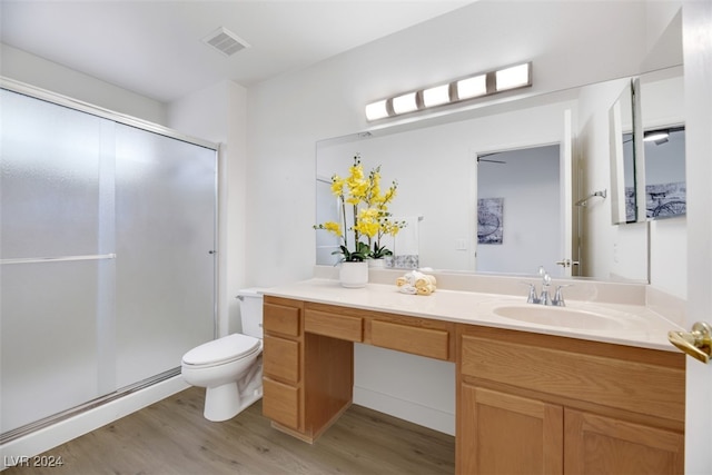 bathroom with vanity, baseboard heating, a shower with door, hardwood / wood-style floors, and toilet