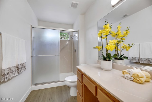 bathroom featuring vanity, toilet, wood-type flooring, and a shower with door