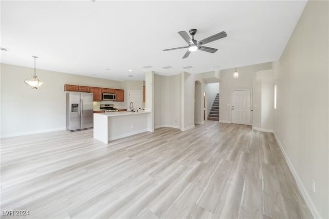 unfurnished living room featuring ceiling fan, sink, and light hardwood / wood-style flooring