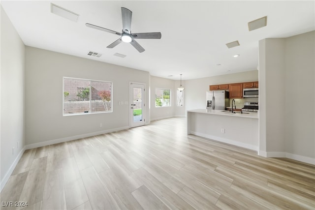 unfurnished living room featuring ceiling fan, light hardwood / wood-style flooring, and sink