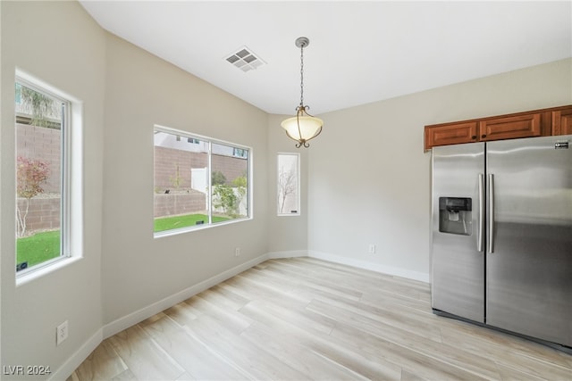 kitchen featuring a wealth of natural light, stainless steel fridge, hanging light fixtures, and light wood-type flooring