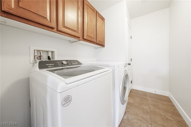 laundry area featuring light tile patterned flooring, cabinets, and independent washer and dryer