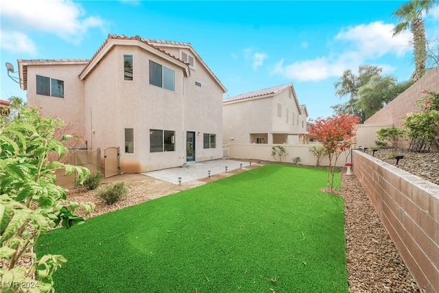 back of house with a yard and a patio