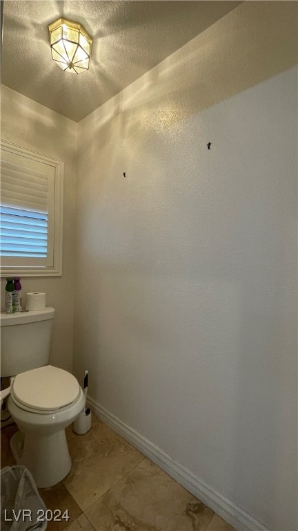 bathroom with tile patterned floors, a textured ceiling, and toilet