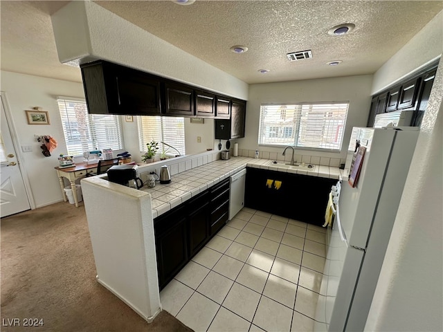 kitchen with tile counters, a healthy amount of sunlight, white refrigerator, and light carpet