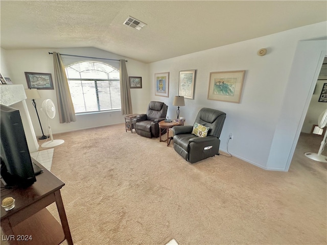 living area with light colored carpet, a textured ceiling, and vaulted ceiling