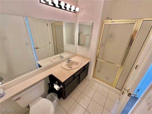 bathroom featuring tile patterned floors, vanity, a shower with shower door, and toilet