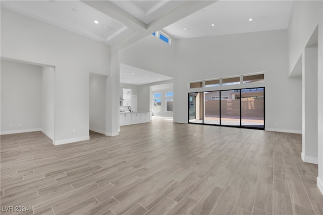 unfurnished living room featuring light hardwood / wood-style floors and a towering ceiling