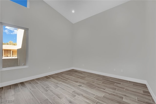 empty room featuring high vaulted ceiling and light hardwood / wood-style flooring