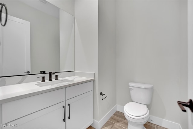 bathroom with hardwood / wood-style floors, vanity, and toilet