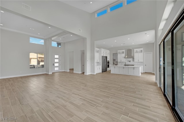 unfurnished living room featuring a towering ceiling and light hardwood / wood-style floors