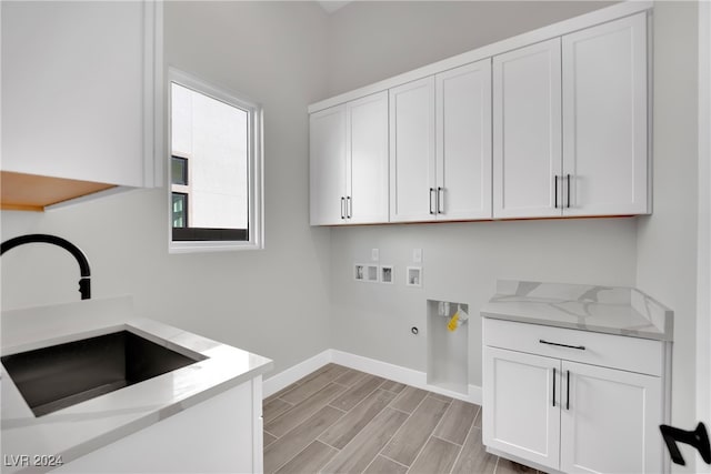 clothes washing area with cabinets, hookup for a washing machine, sink, light hardwood / wood-style flooring, and hookup for a gas dryer