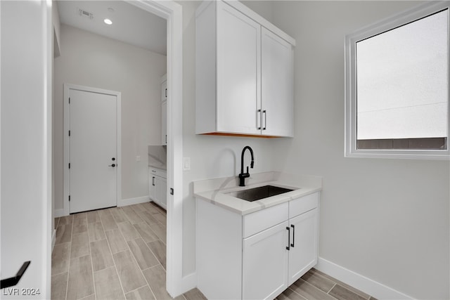 interior space featuring white cabinetry, sink, and light hardwood / wood-style flooring