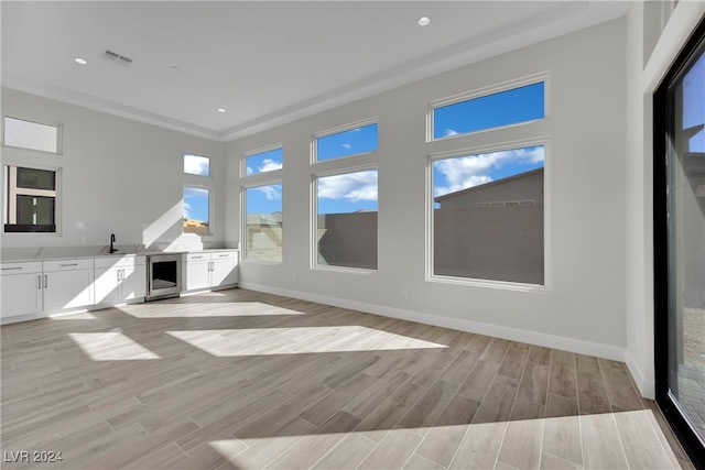 unfurnished living room with light hardwood / wood-style flooring, beverage cooler, and sink