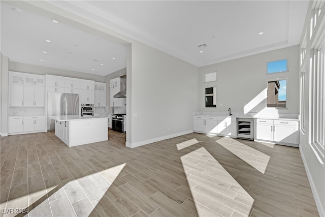 unfurnished living room with wine cooler, sink, and light hardwood / wood-style floors