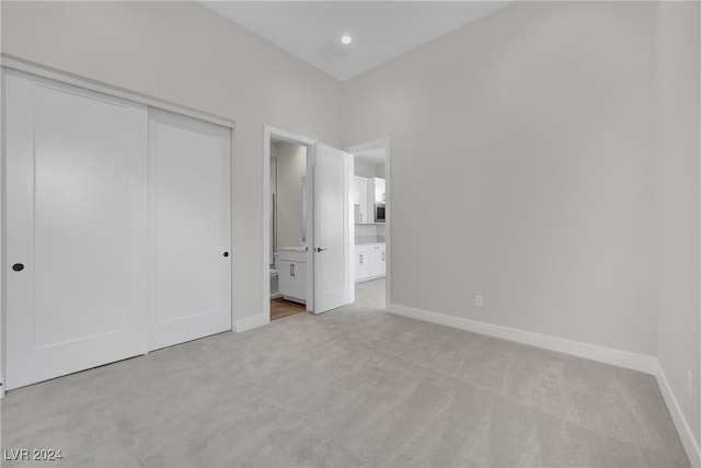 unfurnished bedroom with light colored carpet and a closet