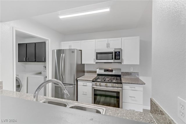 kitchen with sink, stainless steel appliances, washing machine and dryer, light stone countertops, and white cabinets