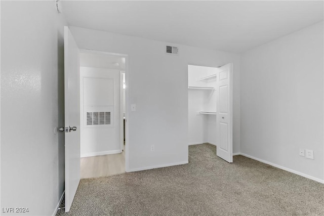 unfurnished bedroom featuring a walk in closet, a closet, and carpet