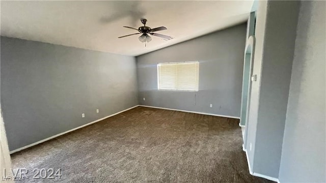 empty room with ceiling fan, lofted ceiling, and dark colored carpet