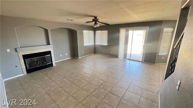 unfurnished living room featuring ceiling fan, light tile patterned floors, and a fireplace