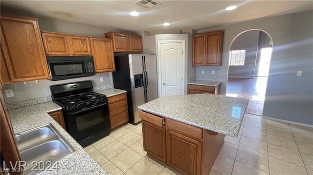 kitchen featuring a center island, light tile patterned flooring, black appliances, and sink