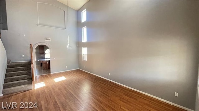 unfurnished living room with a high ceiling and hardwood / wood-style floors