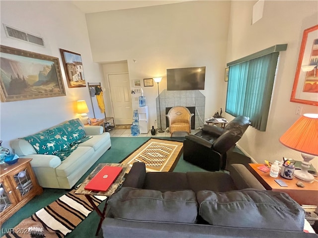 living room with a tile fireplace and a towering ceiling