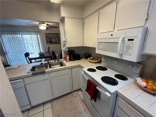 kitchen featuring tile countertops, sink, light tile patterned flooring, and white appliances