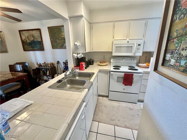 kitchen with tile countertops, white appliances, light carpet, sink, and ceiling fan