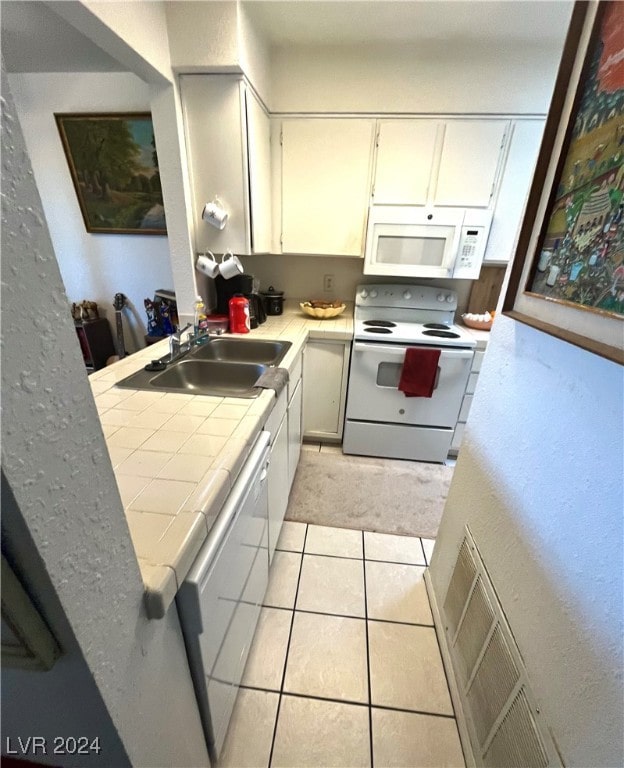 kitchen with sink, light tile patterned flooring, tile countertops, white appliances, and white cabinets