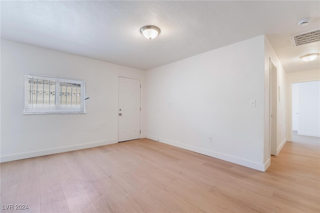 spare room with light hardwood / wood-style floors and a textured ceiling