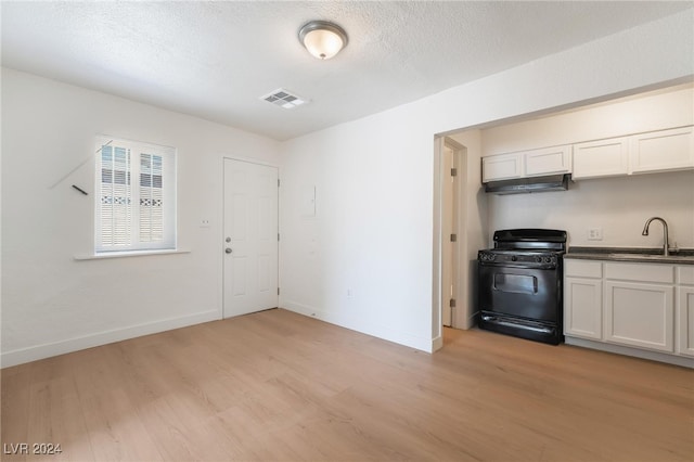 kitchen with white cabinets, light hardwood / wood-style floors, black range, and sink