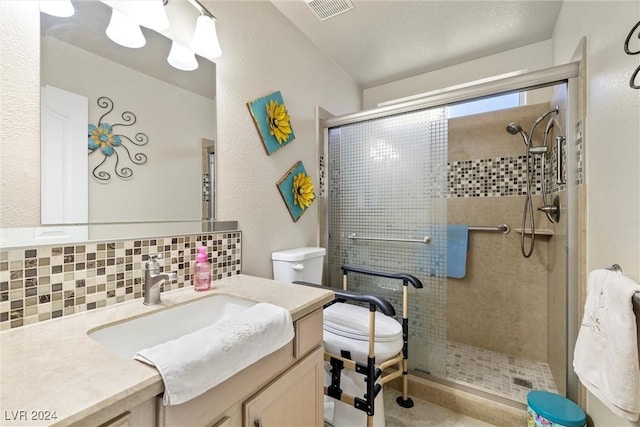 bathroom featuring vanity, toilet, a shower with door, and decorative backsplash