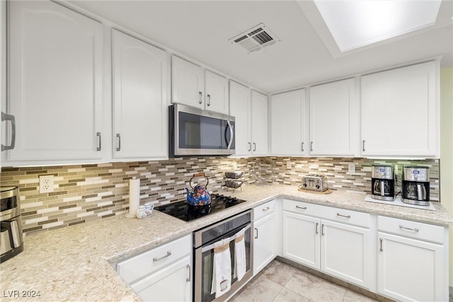 kitchen featuring stainless steel appliances, white cabinetry, and light stone counters