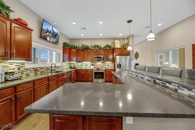 kitchen with a kitchen island, decorative light fixtures, sink, decorative backsplash, and stainless steel appliances